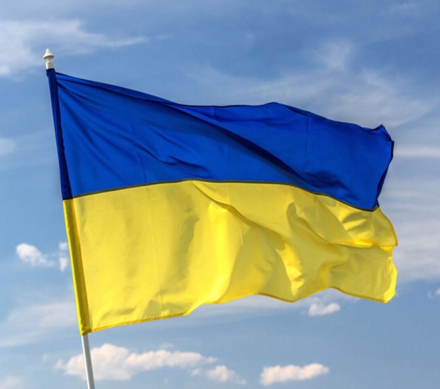 Ukrainsk flagga som fladdrar i vinden mot blå himmelsbakgrund.