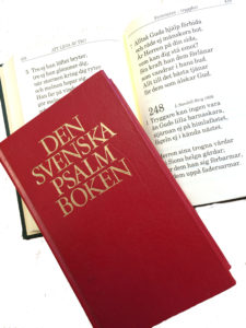 Bild på svenska psalmboken både uppslagen och i helformat.