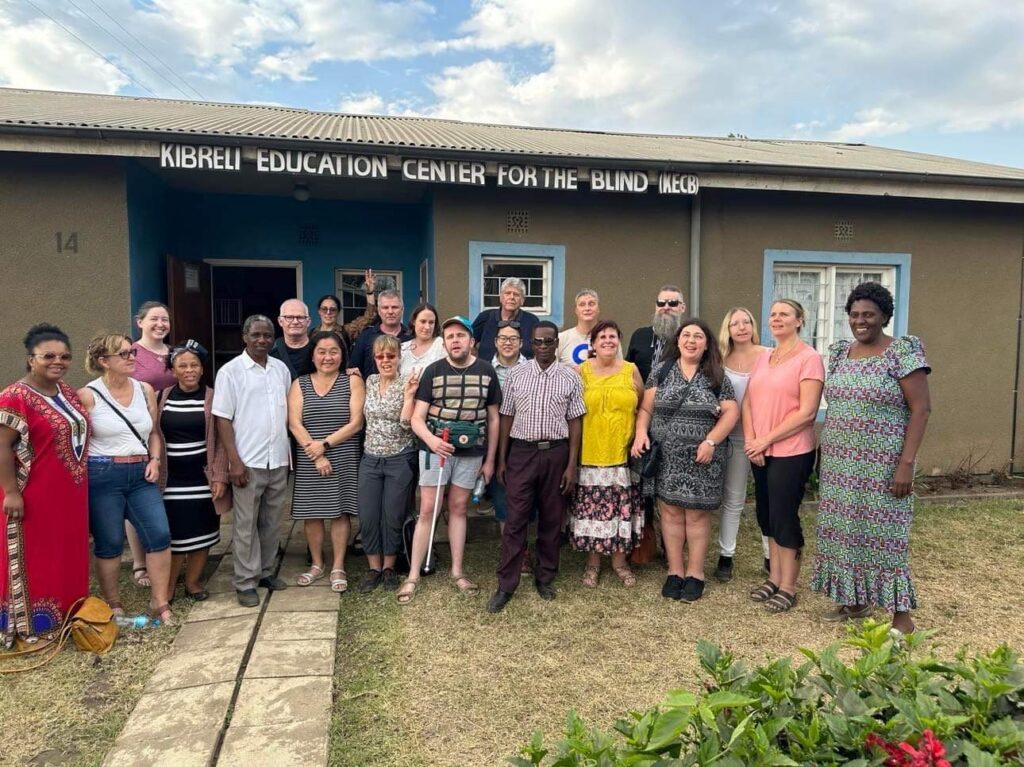 En grupp tillresta Syskonbandare och personal från Kibreli står uppställda utanför centrets byggnad.